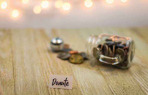 A spilled jar of coins with the word 'Donate' written on a piece of paper